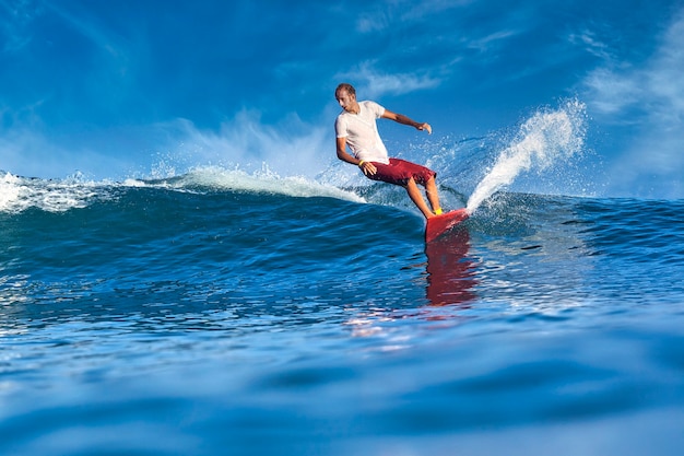 Surfista em uma onda azul em um dia ensolarado