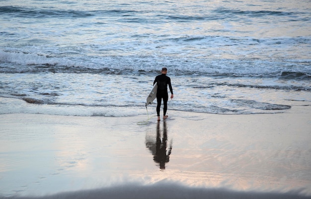 Surfista entrando al agua para practicar surf