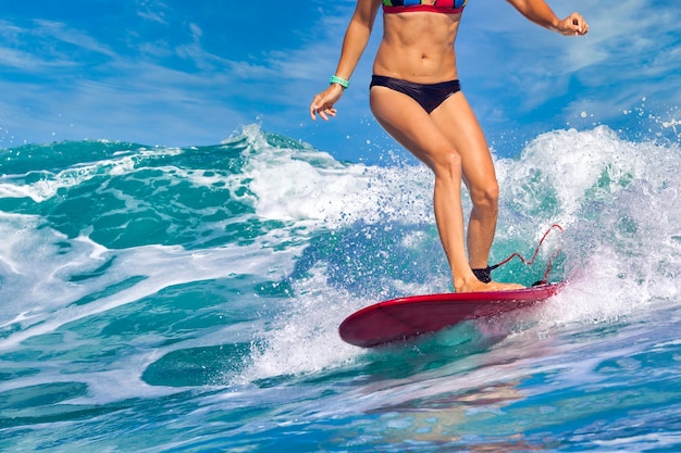 Surfista femenina en una ola azul en un día soleado