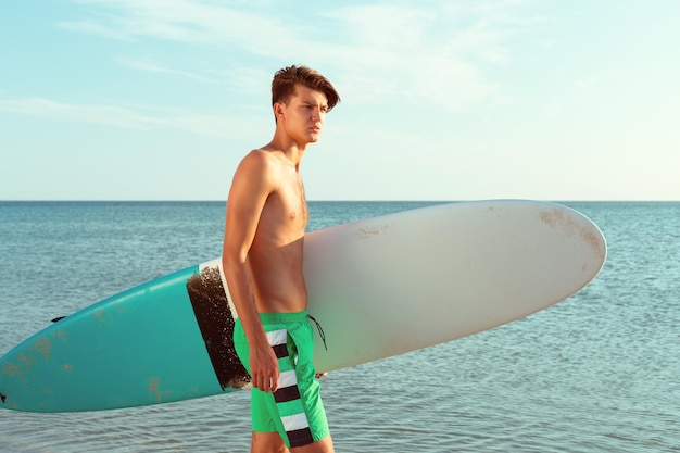 Surfista guapo sosteniendo su tabla de surf