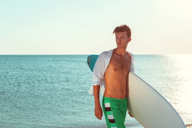 Surfista guapo sosteniendo su tabla de surf