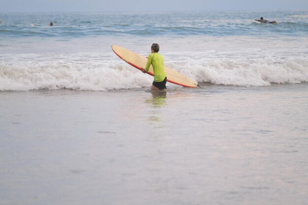 Foto surfista na praia entra no oceano