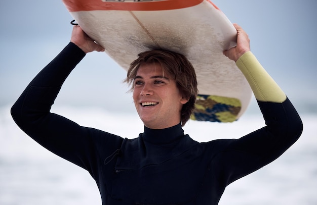 Surfista oceánico y hombre que lleva tabla de surf en vacaciones o viaje de verano en Hawái Ejercicio físico y atleta masculino feliz con tabla después de practicar deportes acuáticos y ejercicio de entrenamiento en el mar