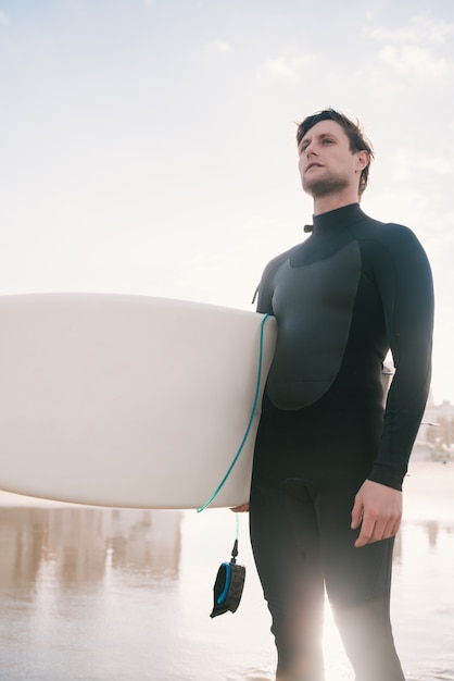 Foto surfista de pie en el océano con su tabla de surf