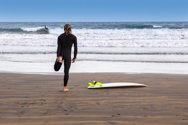 Surfista se aquecendo na praia, ilha de tenerife, espanha