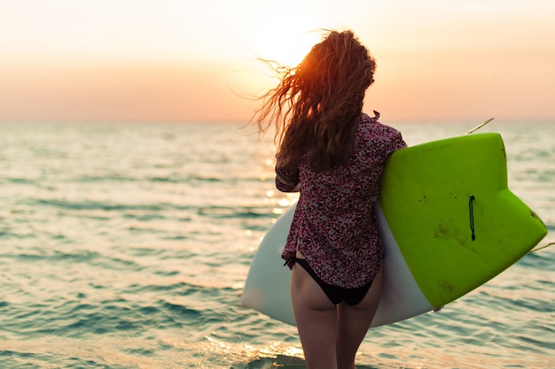 Surfista surfando no pôr do sol na praia do oceano