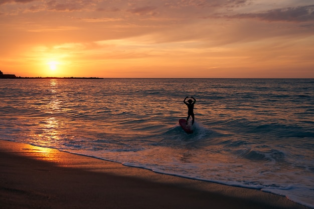 Surfista surfeando una ola con la puesta de sol