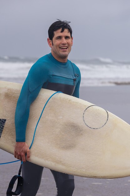 Foto surfista con tabla en un día nublado en la playa