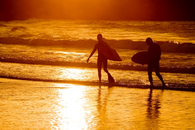 surfistas en una colorida puesta de sol en una zona costera