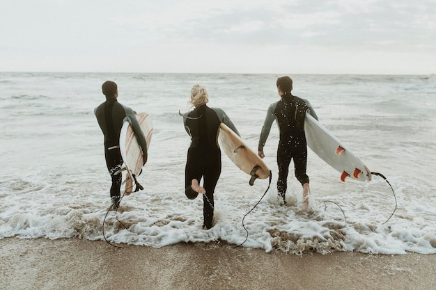 Foto surfistas corriendo hacia el mar
