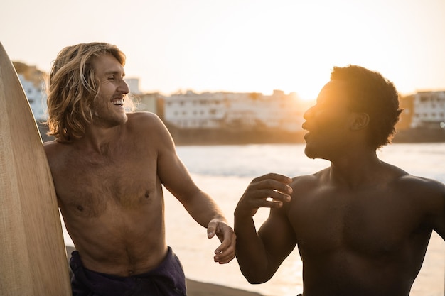 Surfistas multirraciais felizes se divertindo na praia após a sessão de surf