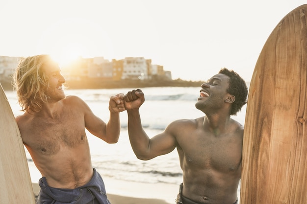 Foto surfistas multirraciais se divertindo na praia - jovens felizes fazendo esportes radicais juntos