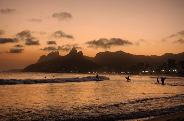 Foto surfistas no mar contra o céu ao pôr-do-sol