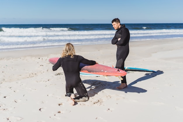 Surflehrer mit einem Kursteilnehmer auf dem Ozean. Surfer in einem Taucheranzug mit einem Trainingsboard