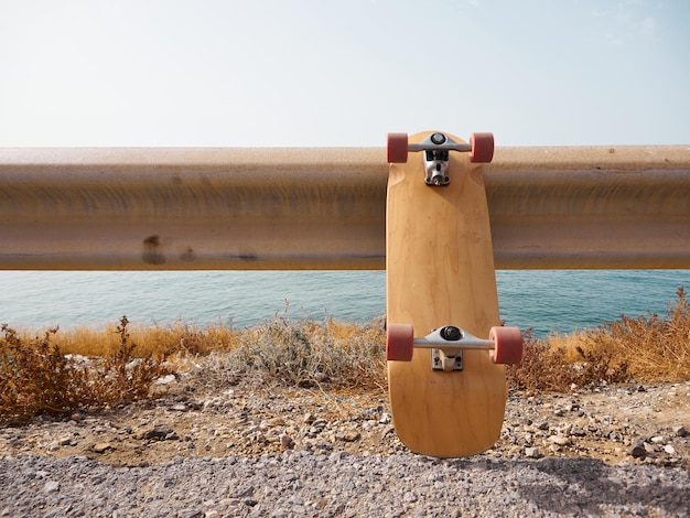 Foto surfskate encostado em um guard rail ao lado do mar