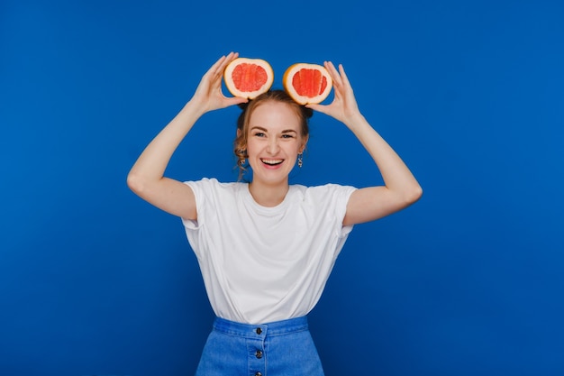 Surpresa, a garota sorridente segura a toranja como orelhas. Estilo de vida vegano. Mulher sorridente, comendo o conceito. Dieta orgânica, perda de peso e alimentação saudável. Smoothies e sucos naturais.