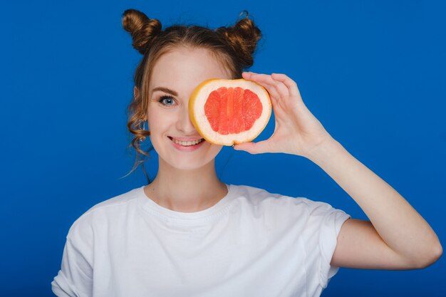 Surpresa, a garota sorridente segura a toranja como orelhas