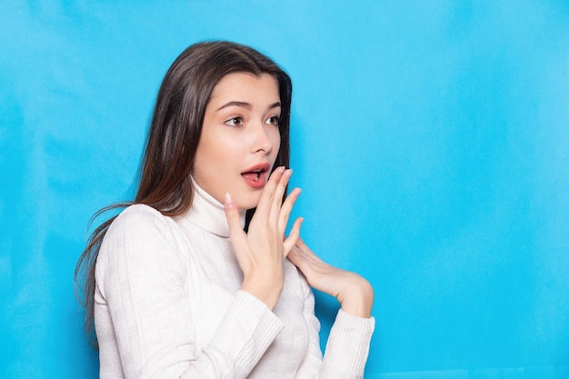 Surpresa chocada jovem morena menina em roupas brancas casuais posando isolado no fundo da parede azul pastel retrato de estúdio Pessoas conceito de estilo de vida Mock up cópia espaço Mantendo a boca aberta