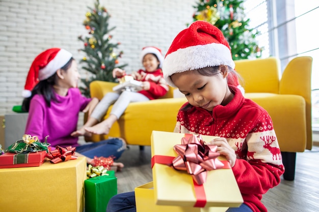 surpresa de garotas asiáticas com presente e ajudando a decorar juntos para comemorar no festival de Natal