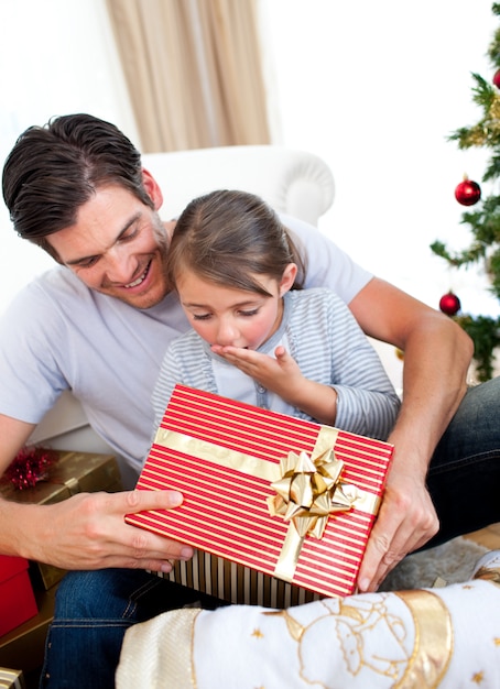 Surpresa filhinha abrindo um presente de Natal com seu pai