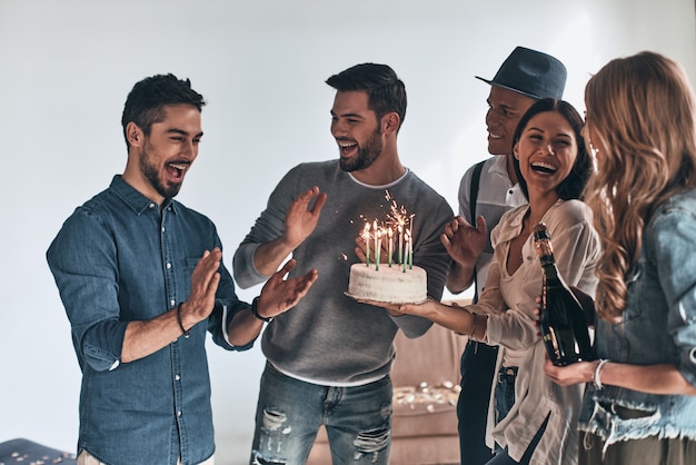 Surpresa! Jovem feliz gesticulando e sorrindo enquanto celebra o aniversário entre amigos