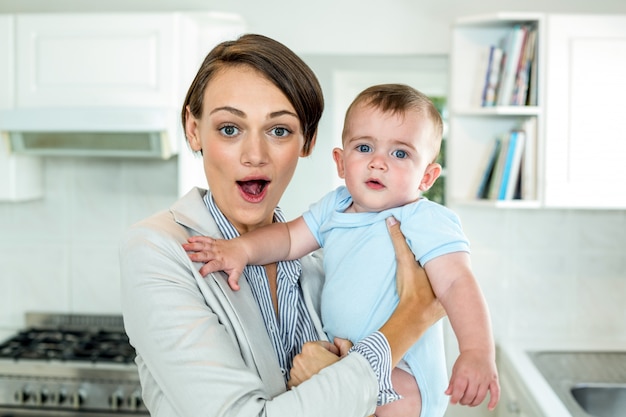 Surpresa mãe carregando filho na cozinha em casa