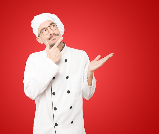 Surpreso jovem chef fazendo um gesto de dúvida