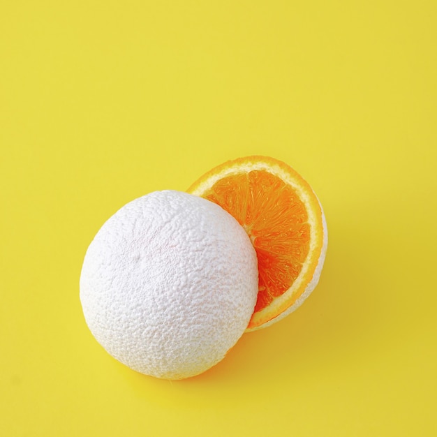 Surreale Idee von unwirklichen weiß geschnittenen Orangenfrüchten auf gelbem Hintergrund.