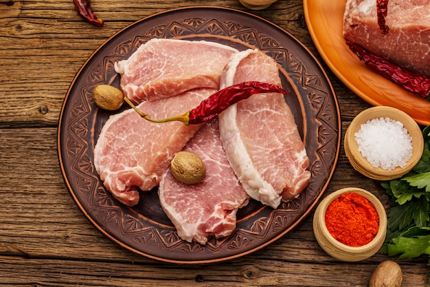 Surtido de carne de cerdo cruda. Lomo fresco, especias, verduras aromáticas y perejil.