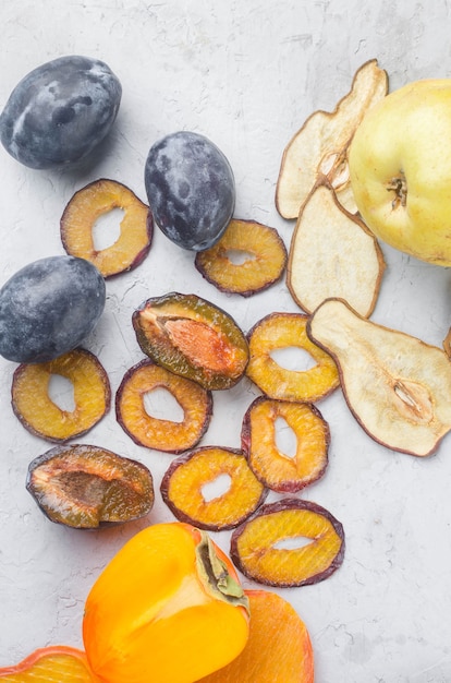 Surtido de chips secos y frutas maduras sobre fondo gris. Chips de frutas. Concepto de alimentación saludable, merienda, sin azúcar. Vista superior, espacio de copia.