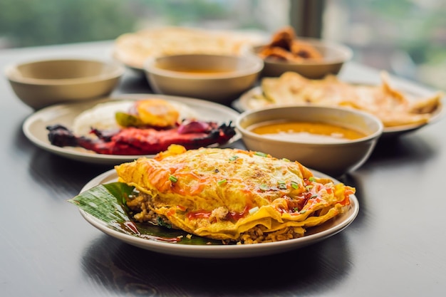 Surtido de comida india sobre fondo de madera oscura. Platos y entrantes de la cocina india. Curry, pollo a la mantequilla, arroz, lentejas, paneer, samosa, naan, chutney, especias. Cuencos y platos con comida india.