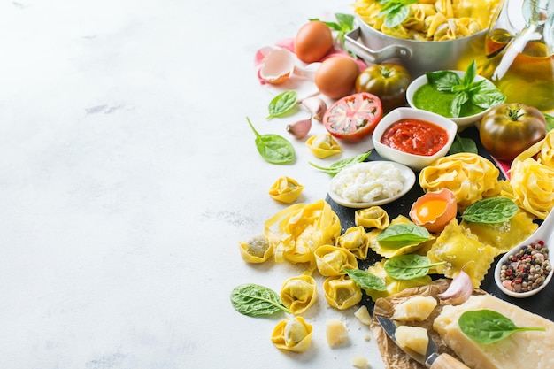 Surtido de comida italiana e ingredientes ravioles con ricotta y pasta de espinacas espaguetis al pesto salsa de tomate aceite de oliva queso parmesano Fondo del espacio de copia