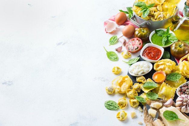 Surtido de comida italiana e ingredientes ravioles con ricotta y pasta de espinacas espaguetis al pesto salsa de tomate aceite de oliva queso parmesano Fondo del espacio de copia