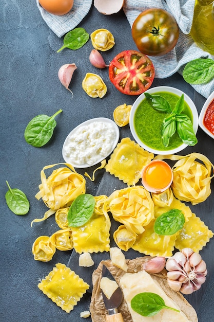 Surtido de comida italiana e ingredientes ravioles con ricotta y pasta de espinacas tortellini pesto salsa de tomate aceite de oliva queso parmesano Vista superior endecha plana