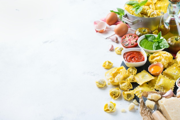 Surtido de comida italiana e ingredientes ravioli pasta espagueti pesto salsa de tomate aceite de oliva queso parmesano Fondo del espacio de copia