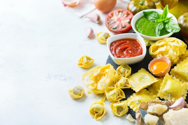 Surtido de comida italiana e ingredientes ravioli pasta espagueti pesto salsa de tomate aceite de oliva queso parmesano Fondo del espacio de copia