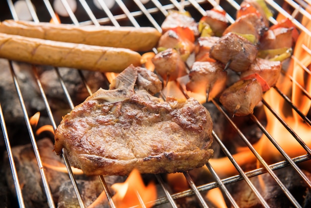 Foto surtido de deliciosas carnes a la parrilla sobre las brasas en una barbacoa.