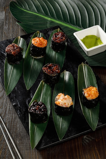 Surtido de diferentes rollos de sushi servidos en plato negro