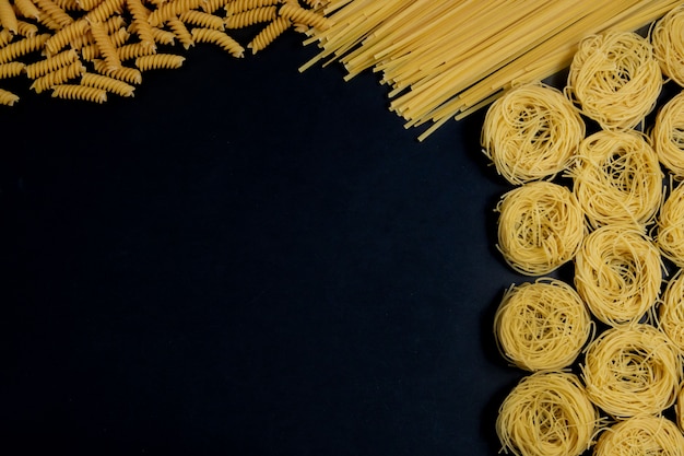 Foto surtido de diferentes tipos de pasta seca sobre fondo negro.