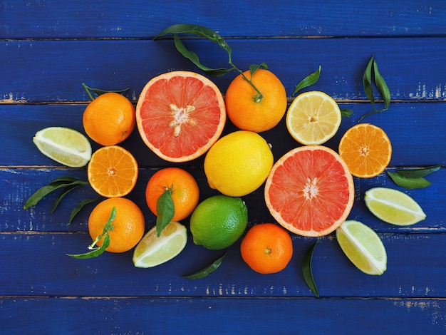 Surtido de frutas cítricas en la superficie de madera azul - naranjas, limones, lima, mandarina y pomelo