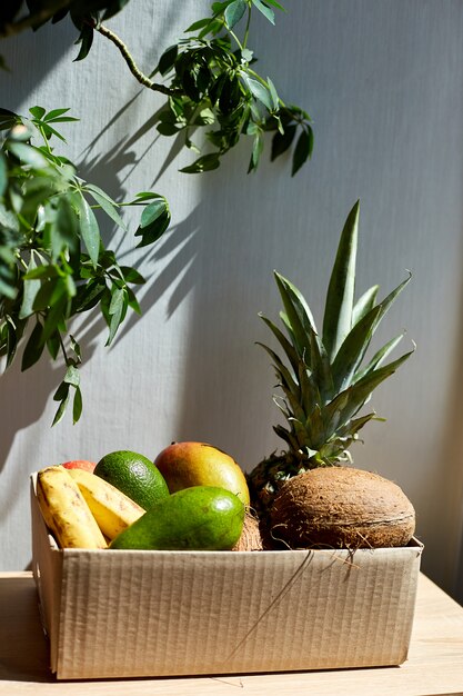 Surtido de frutas exóticas orgánicas en caja, luz solar.