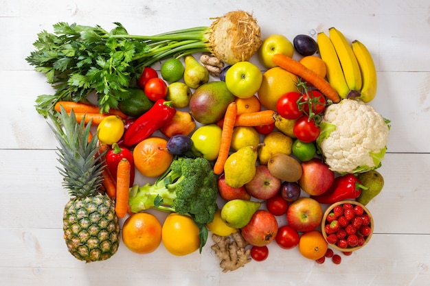 Surtido de frutas y verduras sobre fondo de madera blanca