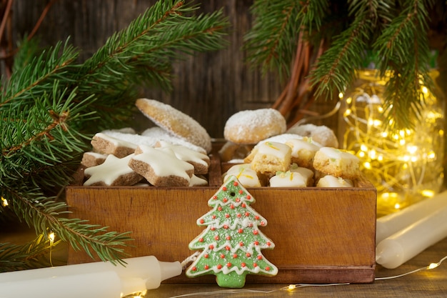 Surtido de galletas navideñas: estrellas de canela, medias lunas de vainilla, cubitos de jengibre y stollen en una caja de madera. Estilo rústico