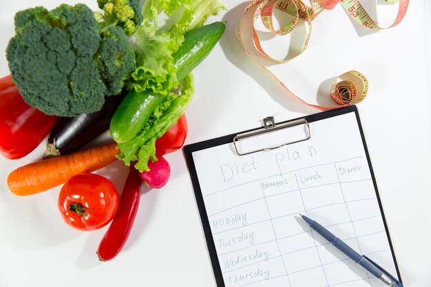 Surtido de ingredientes de nutrición vegetariana cinta métrica y cuaderno con plan de dieta