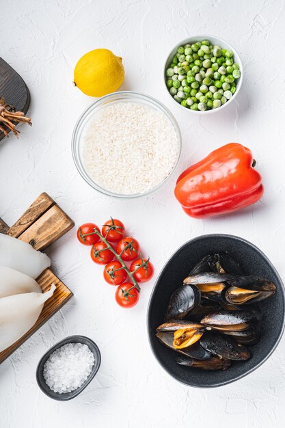 Surtido de mariscos frescos para paella sobre fondo blanco con textura, endecha plana