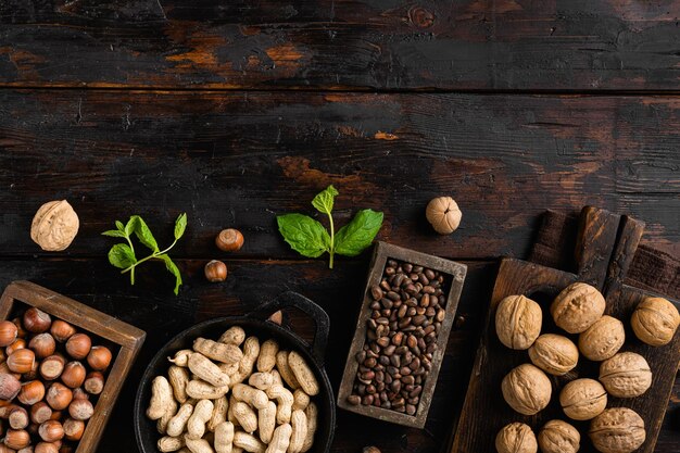 Surtido de nueces en cáscaras de maní, nueces, piñones y avellanas en la vista superior del fondo de la mesa de madera oscura vieja plana con espacio de copia para texto