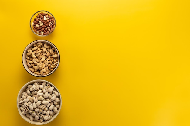 Foto surtido de nueces, pistachos, anacardos y cacahuetescopiar espacio fondo amarillo