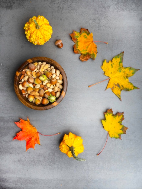 Surtido de nueces y semillas de calabaza en un tazón de madera hojas de otoño calabaza