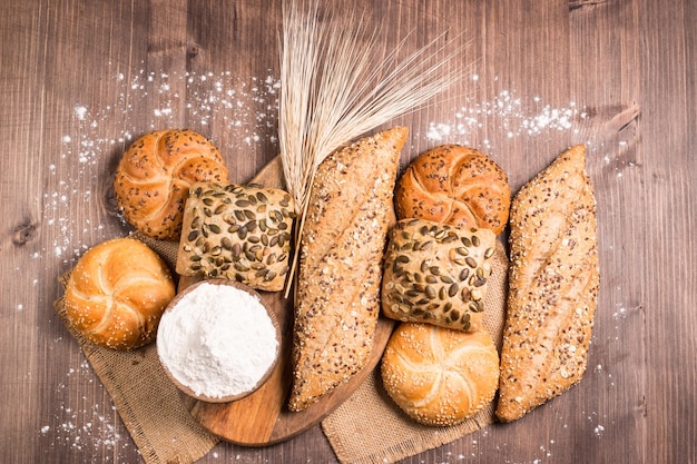 Surtido de pan horneado con semillas sobre un fondo de mesa de madera. Panadería. Concepto de seguridad alimentaria.