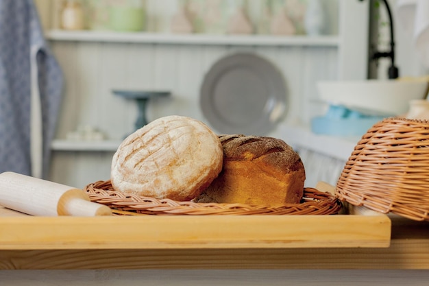 Surtido de panes cerca de una cesta de mimbre sobre una mesa en una cocina rústica Composición en cocina en el estudio fotográfico